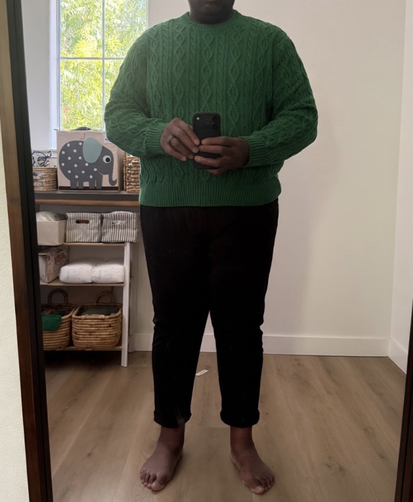 A full-length mirror shot of a knit sweater and dark trousers