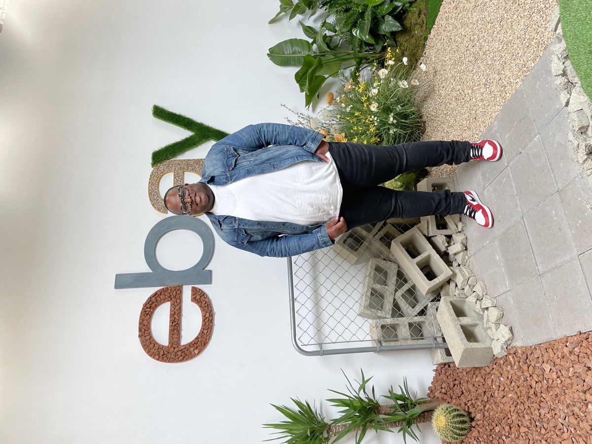 A full-length photo of a denim jacket, white t-shirt, black jeans and high-top sneakers