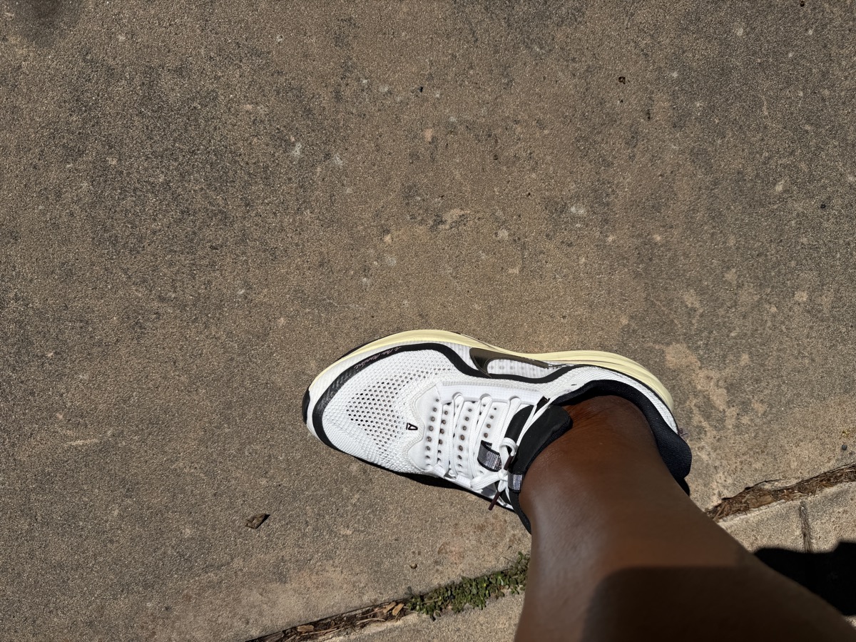 A sneaker photographed from above while being worn, in harsh shadow